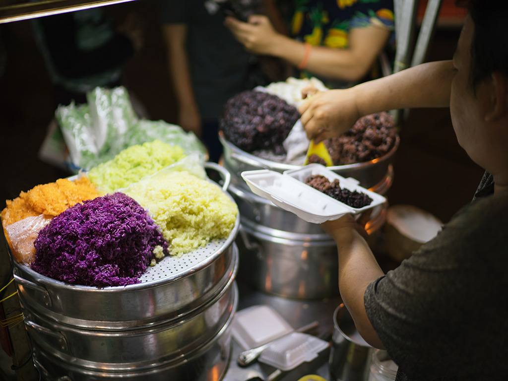 Sweet sticky rice with many colors and flavors is displayed on steam pots. Every time the vendor owner lifts the lid, a huge puff of steam is released, carrying the pleasant fragrance to the air and attracting any bypassers.
